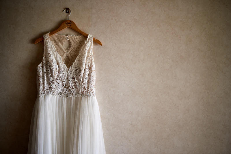 A lace wedding gown hanging on a wooden hanger