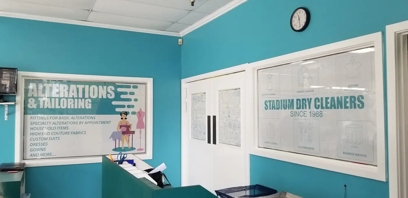 Inside a Stadium Dry Cleaners store, with the alterations and tailoring sign on teal walls